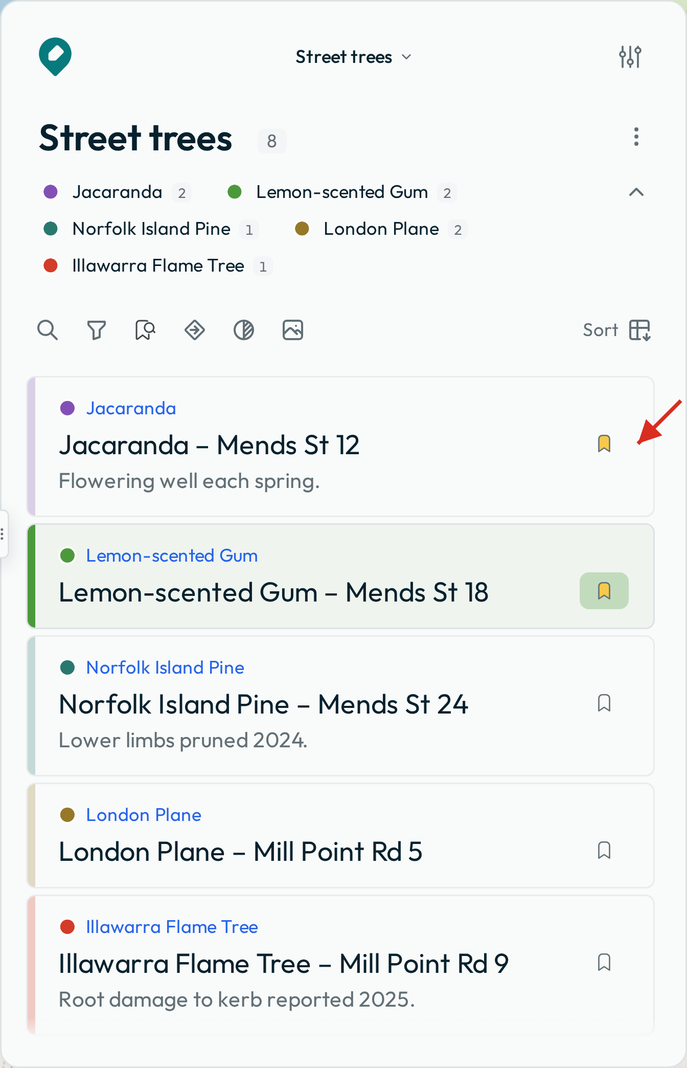 The feature list on the trees layer with two features bookmarked, with their bookmark icons filled, and an arrow pointing at one.